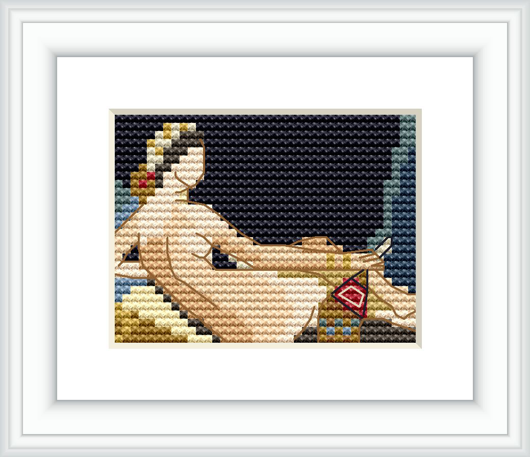 The image shows a cross stitch pattern of a reclining woman with pale skin against a dark background. She is partially draped with fabric and positioned in a serene pose with an ornamented object beside her.