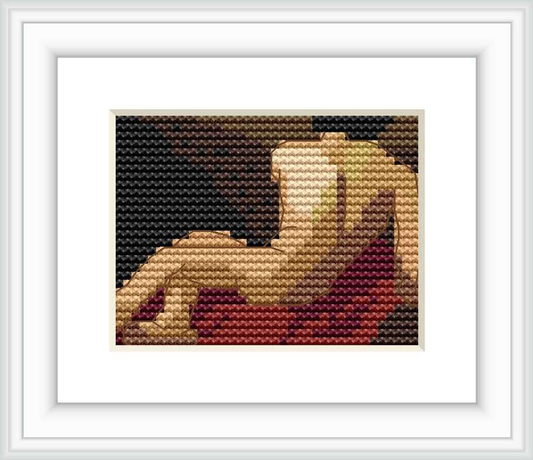 Framed cross stitch of a reclining classical figure, captured in profile against a dark backdrop with warm, earthy tones predominating.