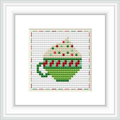 The image displays a square cross stitch pattern with a green and red mug depicted in the center. The mug has a heart design and is surrounded by a border of cross-stitched hearts on a white background. It is matted in a frame for presentation.