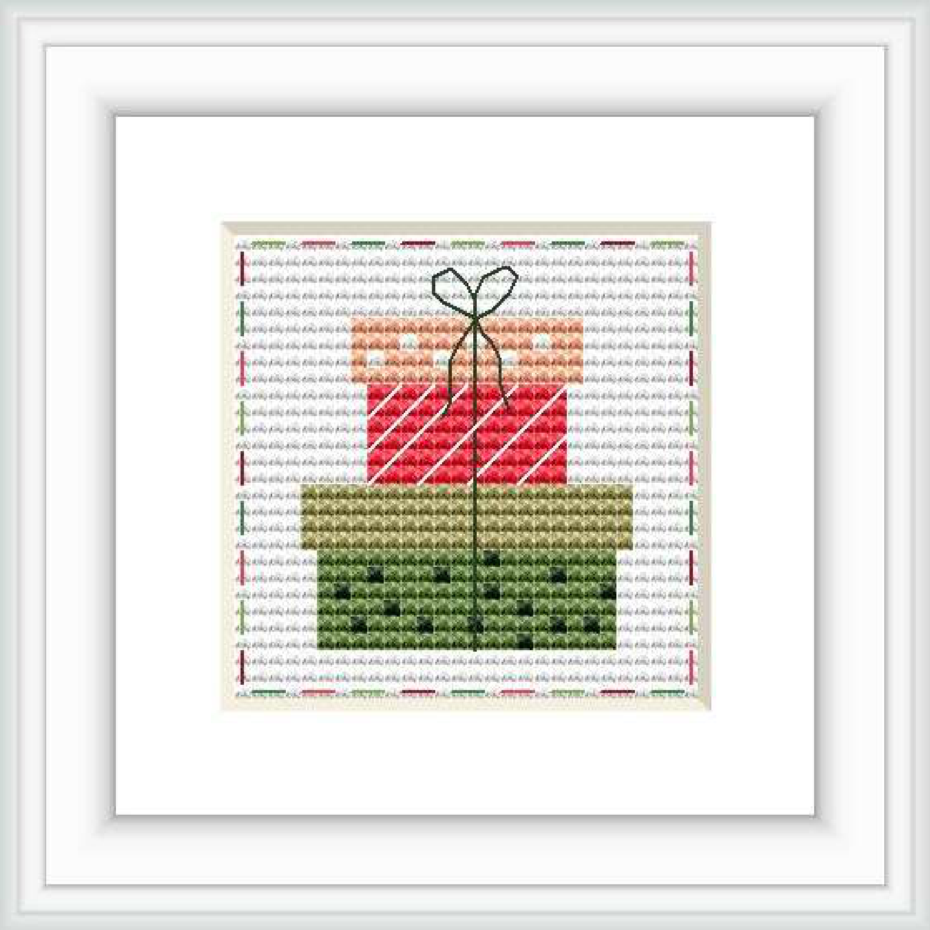 The image shows a cross stitch pattern framed in white, depicting a stylized gift box with a bow on top. The pattern is set against a patterned background with faint script text. The gift box has diagonal red and white stripes, and the bow appears to be a darker shade of green.