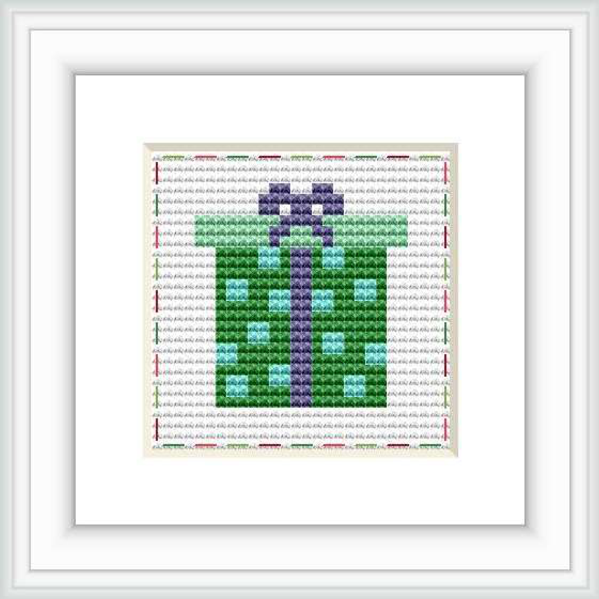 This is a framed cross stitch image depicting a stylized wrapped gift with a bow, primarily in green and purple hues. It's set on a white background with red and grey decorative stitches around the border.