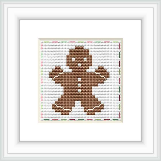 The image shows a completed cross stitch pattern of a gingerbread man centered on a white background, within a square frame. The pattern is detailed with colors mainly in shades of brown, with accent lines suggesting the gingerbread man's features and outlines.