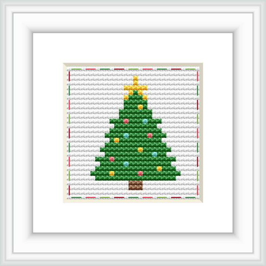 The image shows a framed cross stitch pattern of a Christmas tree with a white background. The tree is embellished with yellow and red ornaments and a gold star on top, set against a stitched backdrop of horizontal lines with small red accents.