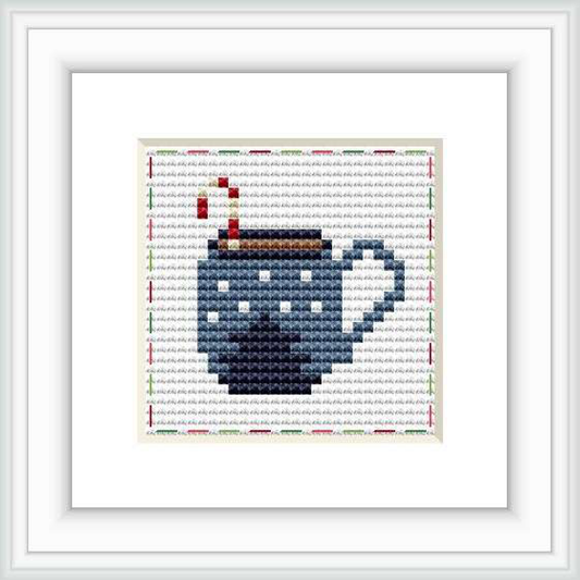 The image presents a framed cross stitch design with a motif of a steaming mug on a dual-tone background with a decorative border.