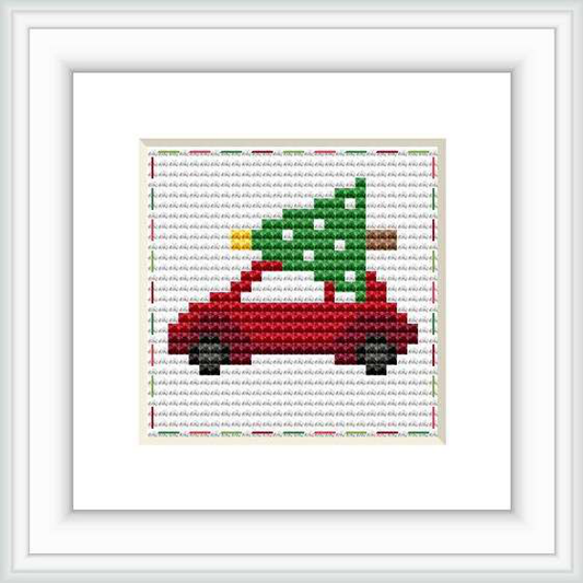 A red car viewed from the side with a green and brown Christmas tree tied to the roof. Displayed on a stitched grid with a white border.