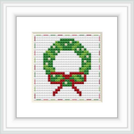 The image shows a framed cross stitch pattern of a holiday wreath with a red bow, against a white background. The stitches are visible and display a 28 by 28 grid pattern.