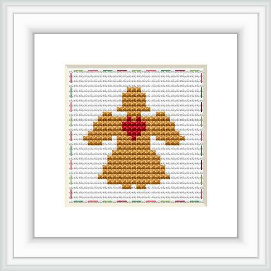 The image displays a framed cross stitch pattern of an angel centered within the composition, predominantly in shades of gold and with a red heart at its core. The background is made up of rows of horizontal stitches in a variety of colors creating a textured effect.