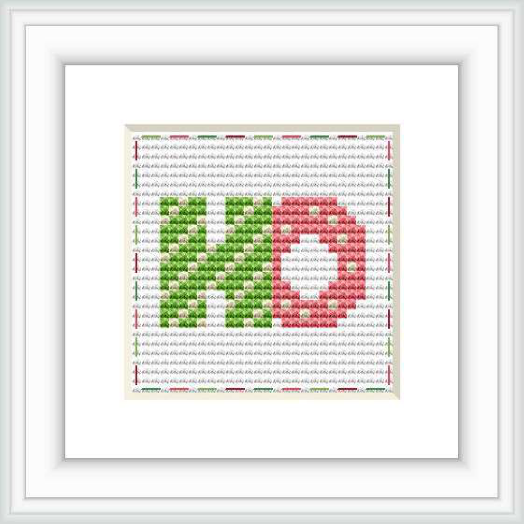 The image features a framed cross stitch pattern with the letters 'HO' centered on it. The letters are in a block style, with the 'H' in green and the 'O' in red, set against a background that fades from grey at the top to white at the bottom, with tiny red and green dots simulating a festive pattern.