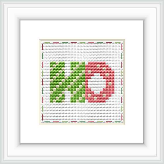 The image features a framed cross stitch pattern with the letters 'HO' centered on it. The letters are in a block style, with the 'H' in green and the 'O' in red, set against a background that fades from grey at the top to white at the bottom, with tiny red and green dots simulating a festive pattern.