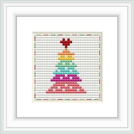 The image displays a framed cross stitch pattern depicting a Christmas tree with a pixelated, rainbow color gradient against a neutral patterned background.