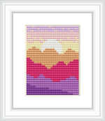 The image depicts a cross stitch pattern with a minimalist design of a mountain landscape. There are layers of mountains, each in different pastel shades creating the impression of distance. The pattern is framed and the stitches appear even and tidy.