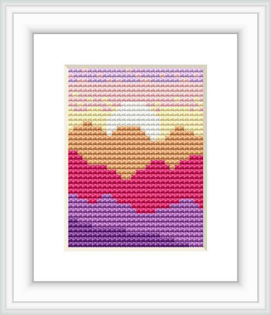 The image depicts a cross stitch pattern with a minimalist design of a mountain landscape. There are layers of mountains, each in different pastel shades creating the impression of distance. The pattern is framed and the stitches appear even and tidy.