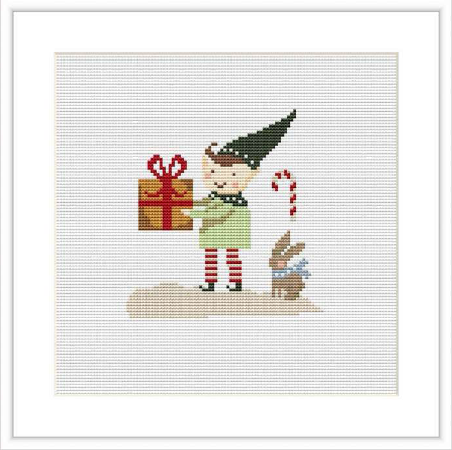 The image displays a cross stitch pattern of a gnome wearing a tall pointy hat, holding a red gift box and a candy cane. Beside the gnome, there is a brown bunny. This takes place on a plain white background, symbolizing snow.