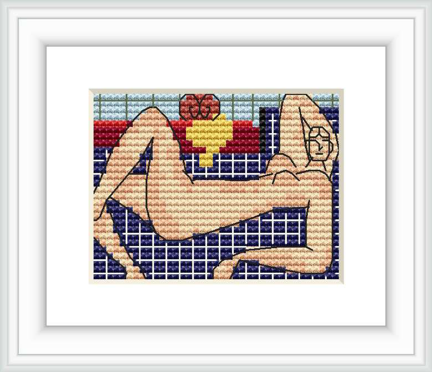 A cross stitch rendering of a reclining nude figure, with sections of different colors and patterns, framed and matted on a wall.