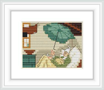 The image shows a cross-stitch pattern representing an indoor scene with a male figure lying on a bed draped in a green blanket, reading beneath an umbrella which seems to be protecting him from a leaky roof. The garret room has a warm palette, with wooden beams and a window.
