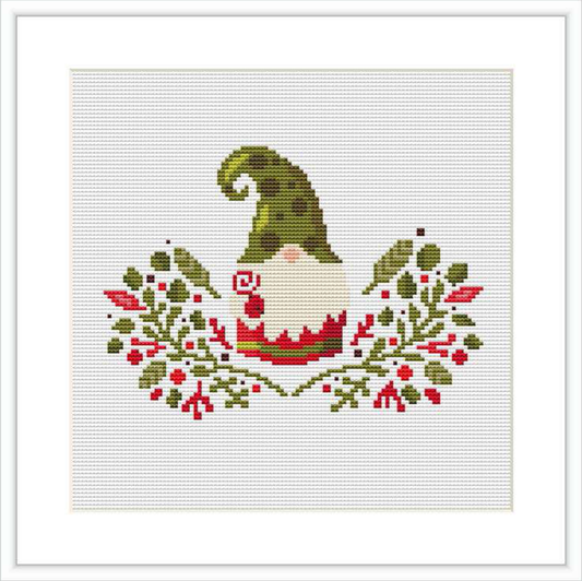 The image shows a cross stitch pattern of a gnome with a tall, bent green hat. The gnome is surrounded by red and green foliage and berried branches, as well as some golden accents.