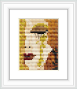 A framed embroidered cross stitch pattern of a stylized woman's face with golden and brown hues, reminiscent of Gustav Klimt's artwork. She appears to have a tear running down from the eye.