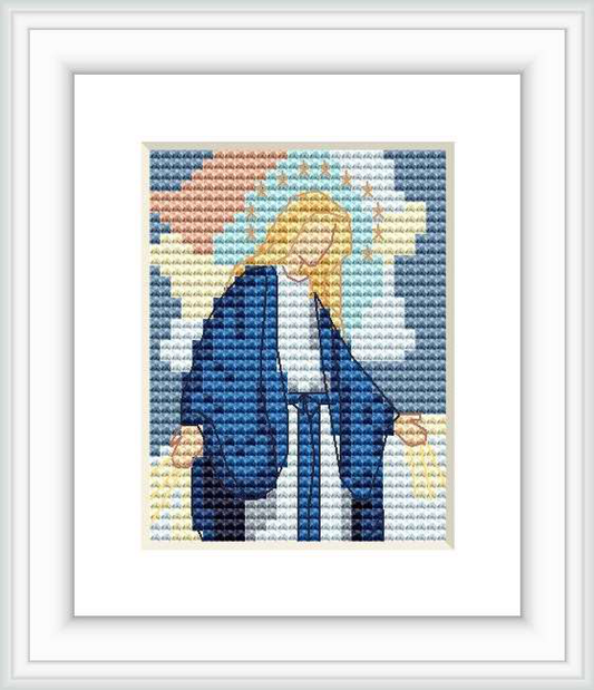 The image depicts a cross stitch pattern framed in white, featuring a stylized representation of the Madonna. Her face is bowed, and she is draped in a blue robe with a greyish background and soft, pastel-like coloration.