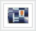 The image shows a framed cross stitch pattern consisting of blocks of color forming a pixelated design, with a dominant central orange block resembling a leaf surrounded by a background of various shades of blue, purple, white, and gray.