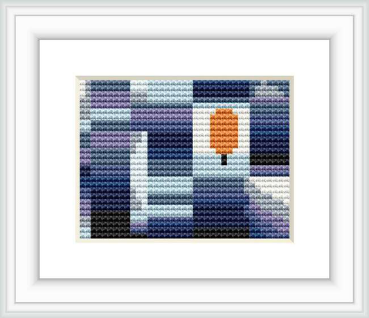 The image shows a framed cross stitch pattern consisting of blocks of color forming a pixelated design, with a dominant central orange block resembling a leaf surrounded by a background of various shades of blue, purple, white, and gray.