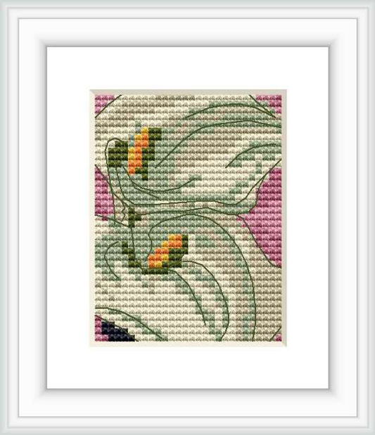 The image depicts a cross stitch pattern of two stylized calla lilies on a pink background. The design is framed, showcasing the intricate stitching and color details.