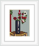 The image depicts a small cross stitch pattern of a still life bouquet of anemones in a vase, placed on a table or flat surface.