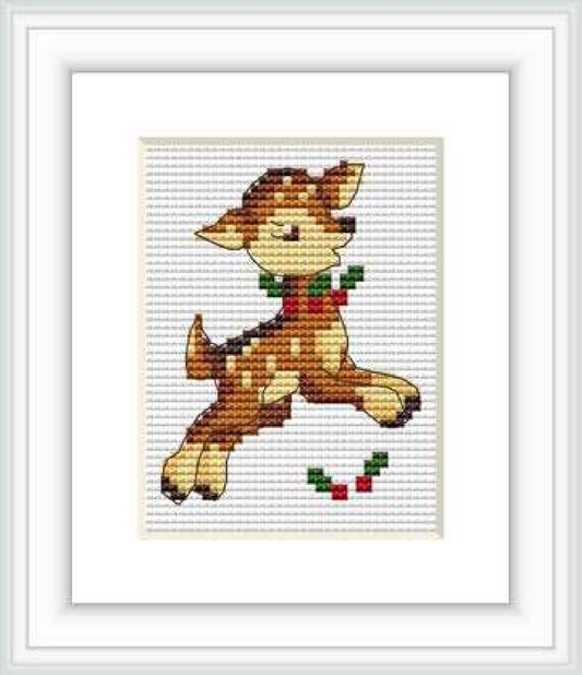 The image depicts a cross stitch pattern of a prancing deer, framed by a white border. The deer is rendered in shades of brown, with a red and green scarf and holly leaves.