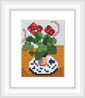 The image depicts a cross stitch pattern of red geraniums in a vase with blue and white patterns, set against an orange and white backdrops.