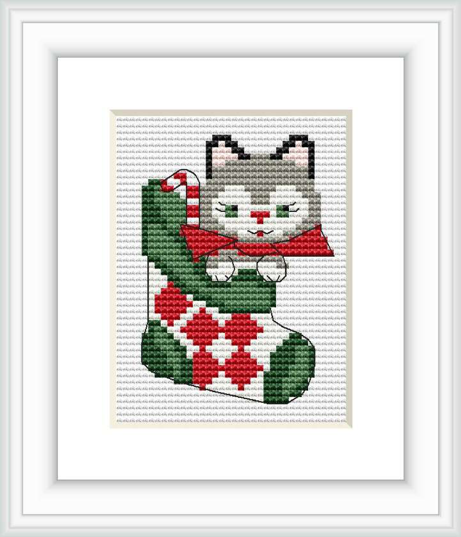 The image depicts a cross stitch pattern of a gray and white cat with a red bow, sitting in a green and red Christmas stocking, set against a plain white background within a picture frame.