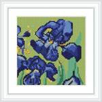 A framed cross stitch pattern of blue and indigo flowers with green leaves on a light green background.