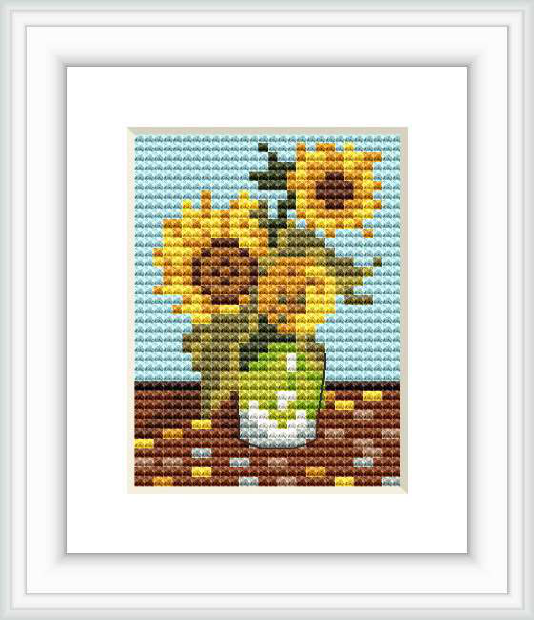 The image depicts a cross stitch pattern of three bright yellow sunflowers in a vase, against a two-toned background with a light blue sky and brown tabletop.