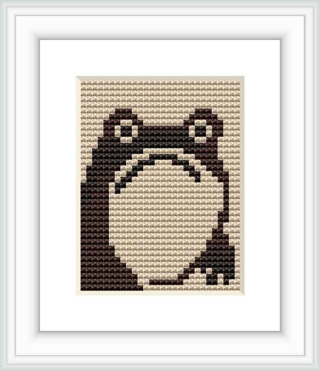The image depicts a cross stitch pattern of a stylized frog with a simplified design, prominently featuring shades of brown against a light background, framed within a square border.