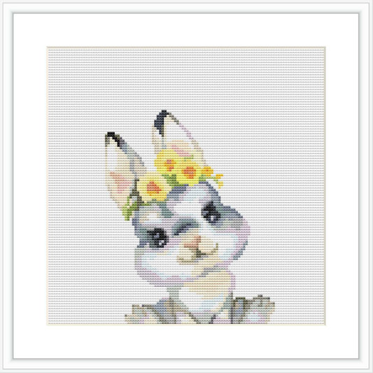 The image shows a cross stitch pattern of a bunny's face with upright ears, decorated with a small crown of yellow flowers and pale green leaves on its head. The surrounding area is a blank canvas.