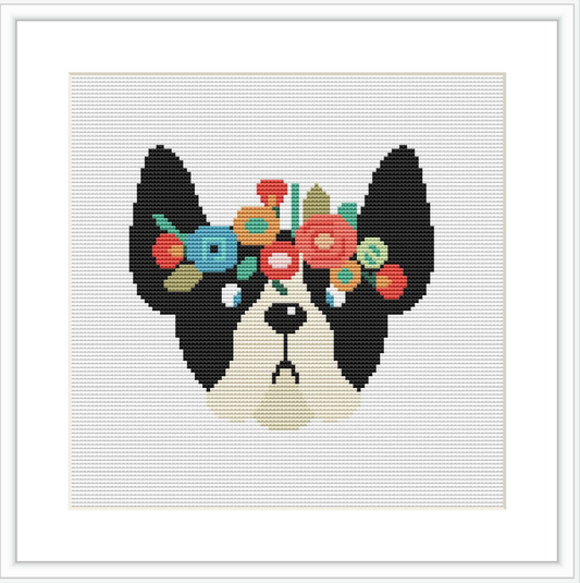 The design depicts the head of a black and white dog facing forward with a colorful floral arrangement on its head. The flowers are in tones of red, green, blue, and yellow. The background is a simple white, highlighting the dog and flowers.