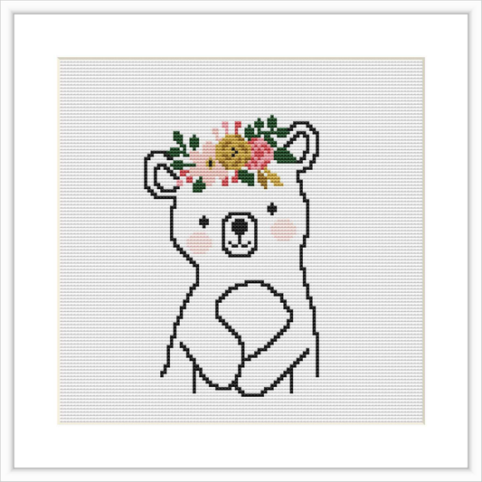 The image shows a cross stitch pattern of a bear with flowers arranged on its head like a crown. The bear is centered on the canvas, with a simple background.