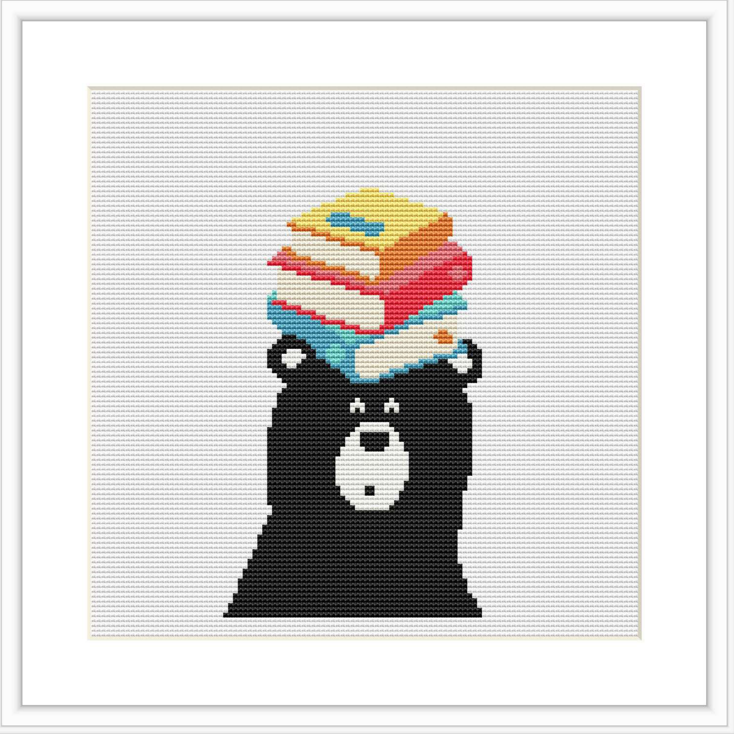 A cross stitch pattern depicting a black bear with a stack of three colorful books on its head. The background is white, and the bear is centered in the frame.