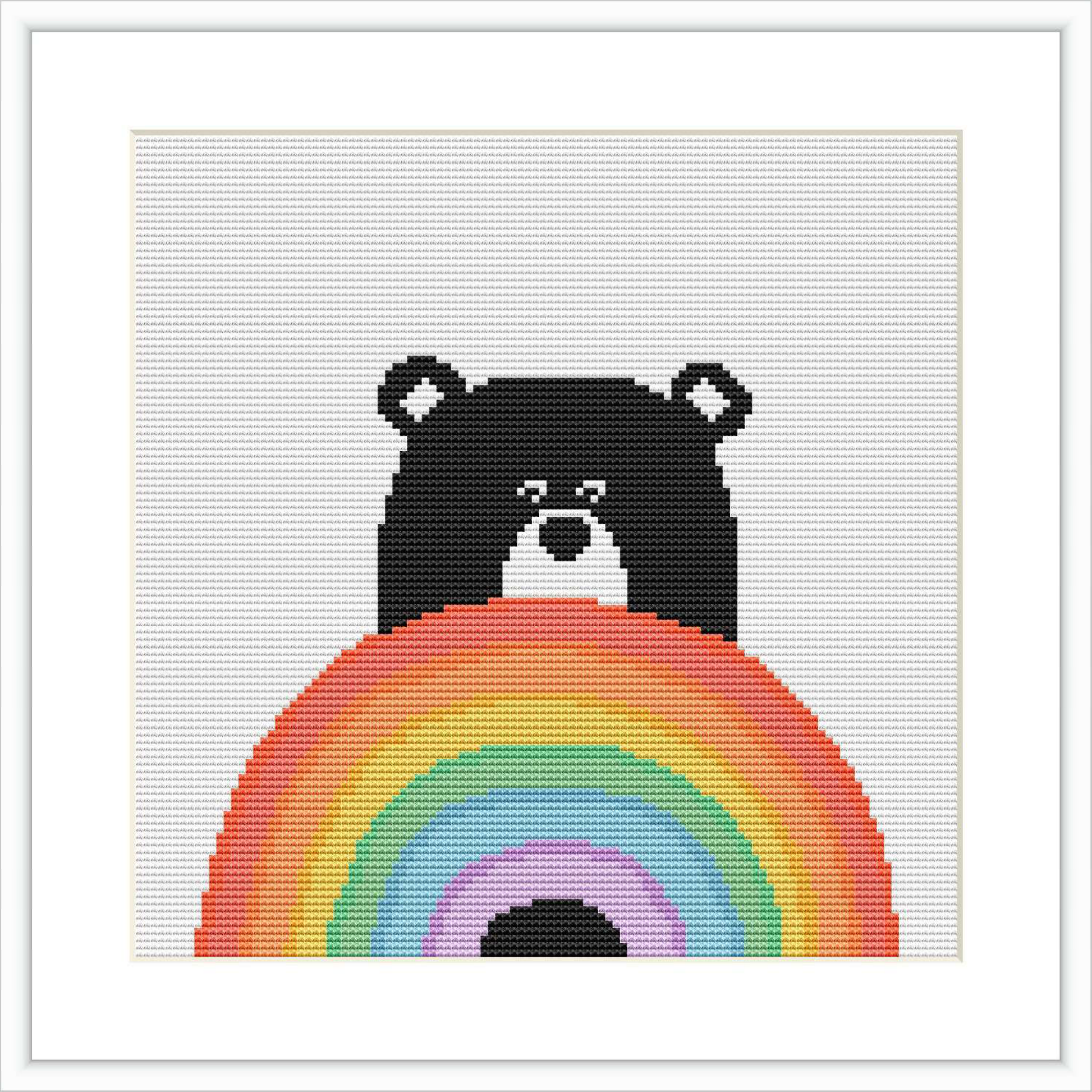 The image displays a cross stitch pattern featuring a black bear with a simple expression. The bear is seen peeking over a large, colorful rainbow that fills the lower half of the frame. The background is plain white.