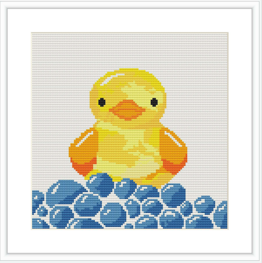 The image displays a cross stitch pattern of a yellow duckling seated amidst numerous blue water droplets. The duckling is in the center with a light blue and white background.