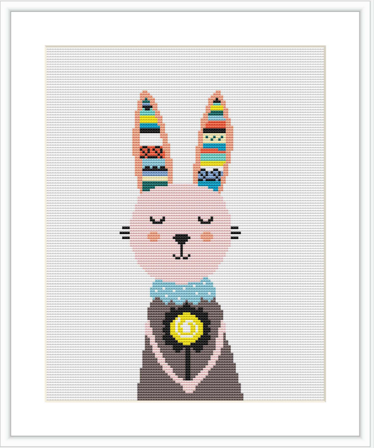 The image displays a cross stitch pattern of a cartoon-style bunny girl. The bunny has closed eyes with long lashes, pink cheeks, and patterned ears. She is dressed in a grey and blue dress with a yellow flower centerpiece, set against a plain white background with a grid.