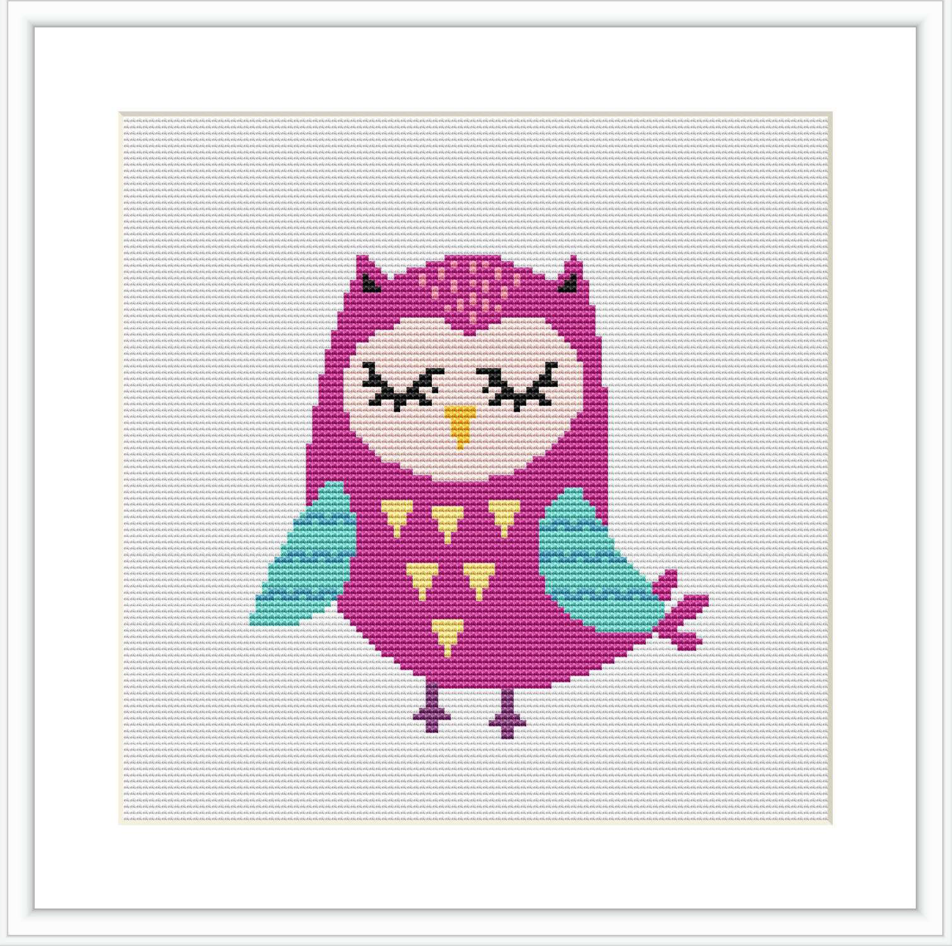 The image shows a framed cross-stitch pattern depicting a stylized owl sitting upright. It has large eyes, a heart-shaped pattern on its chest, and is rendered in shades of pink, turquoise, and yellow.