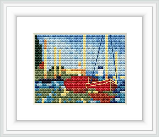 A cross stitch pattern depicting several boats, mainly one prominent red boat, at a harbor with a reflection on the water, surrounded by a serene blue sky.