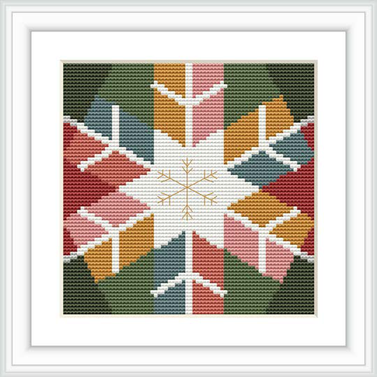 The image displays a framed cross stitch pattern featuring a central snowflake motif surrounded by geometric shapes and winter colors.