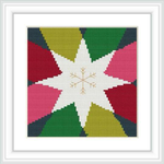 The image showcases a framed cross stitch pattern featuring a large multi-pointed star in the center with segments of red, green, and yellow, bordered by black. Small festive motifs embellish the star, set against a white background.