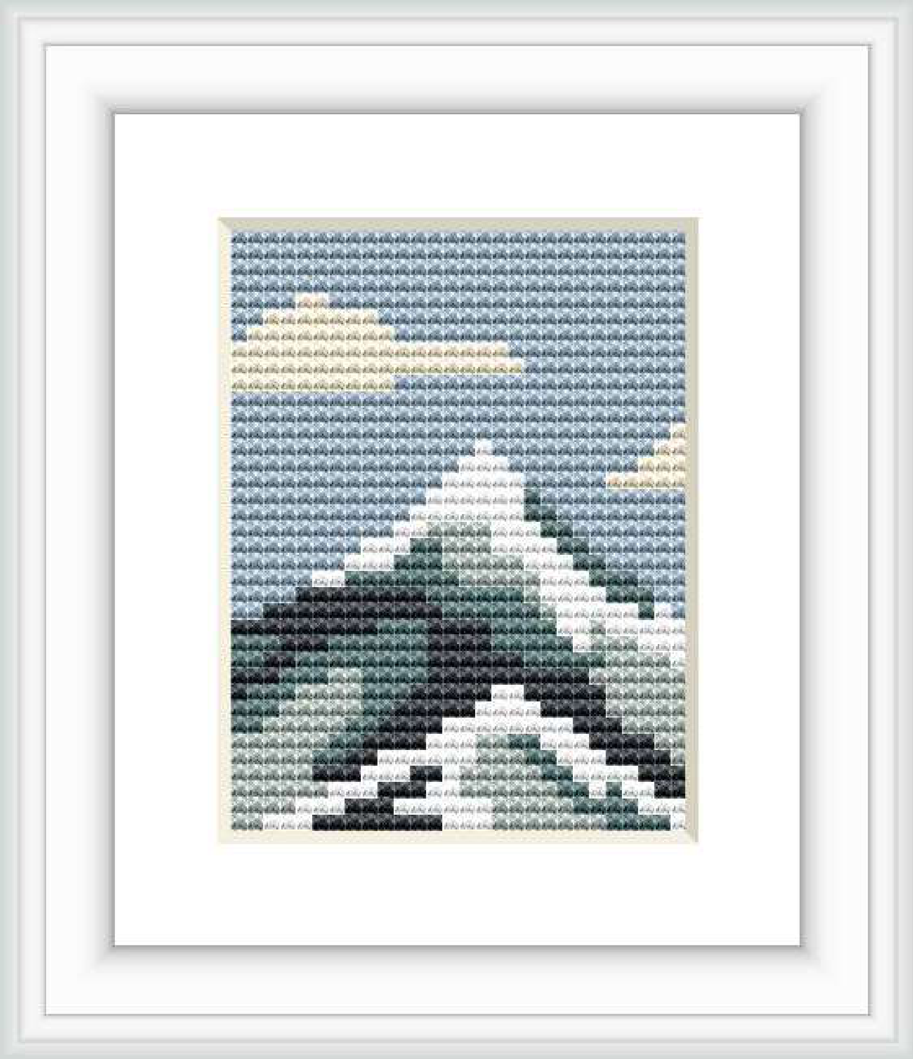 The image depicts a framed cross stitch pattern of a mountain landscape, with shades of blue, white, green, and grey, capturing the essence of a mountain peak with surrounding clouds.