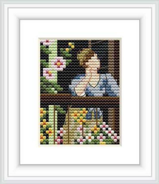 The cross stitch pattern depicts a woman leaning on a balcony with her chin resting on her hand, surrounded by lush flowers in a garden setting.