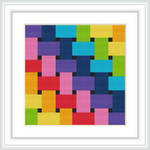 The image shows a framed cross stitch pattern with a colorful geometric design. The pattern is made up of square shapes in various colors neatly stitched into a white fabric, encased within a simple white frame on a white background.