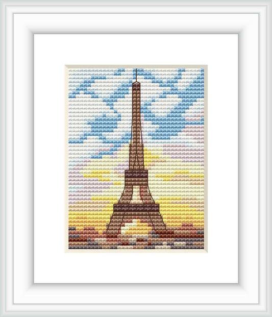 The cross stitch pattern depicts the iconic Eiffel Tower centered on a gradient background that mimics a sunset sky. The sky transitions from a light blue at the top to yellow, and then to brown at the base, resembling the ground. The image is framed within a border, suggesting a finished piece.