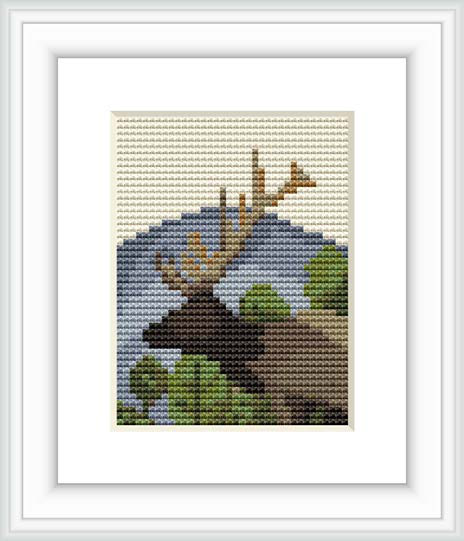 The image portrays a small cross stitch pattern that depicts a mountainous landscape possibly inspired by Canadian scenery, featuring shades of brown, green, and blue with a stylized representation of clouds or sky in the background.