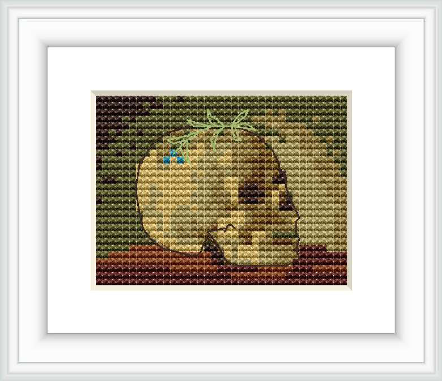 The image depicts a cross stitch pattern of a skull viewed from the side, with the small blue flowers of a forget-me-not positioned near the top left of the skull, set against a background featuring neutral and earthy tones.