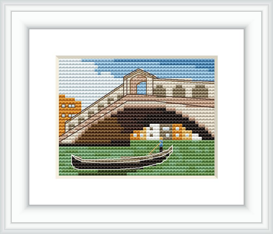 The image depicts a cross stitch embroidery of the Rialto Bridge in Venice with a gondola in the forefront and buildings in the background.